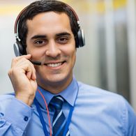 Portrait of happy technician talking on head phones